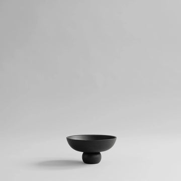 Black ceramic bowl on a light gray background from 101 Copenhagen at Spacio retail stores in Mumbai & Kolkata. 