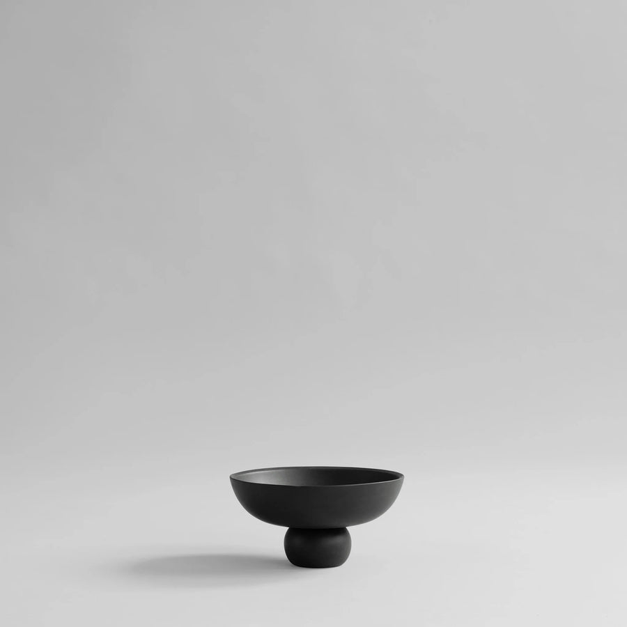 Black ceramic bowl on a light gray background from 101 Copenhagen at Spacio retail stores in Mumbai & Kolkata. 