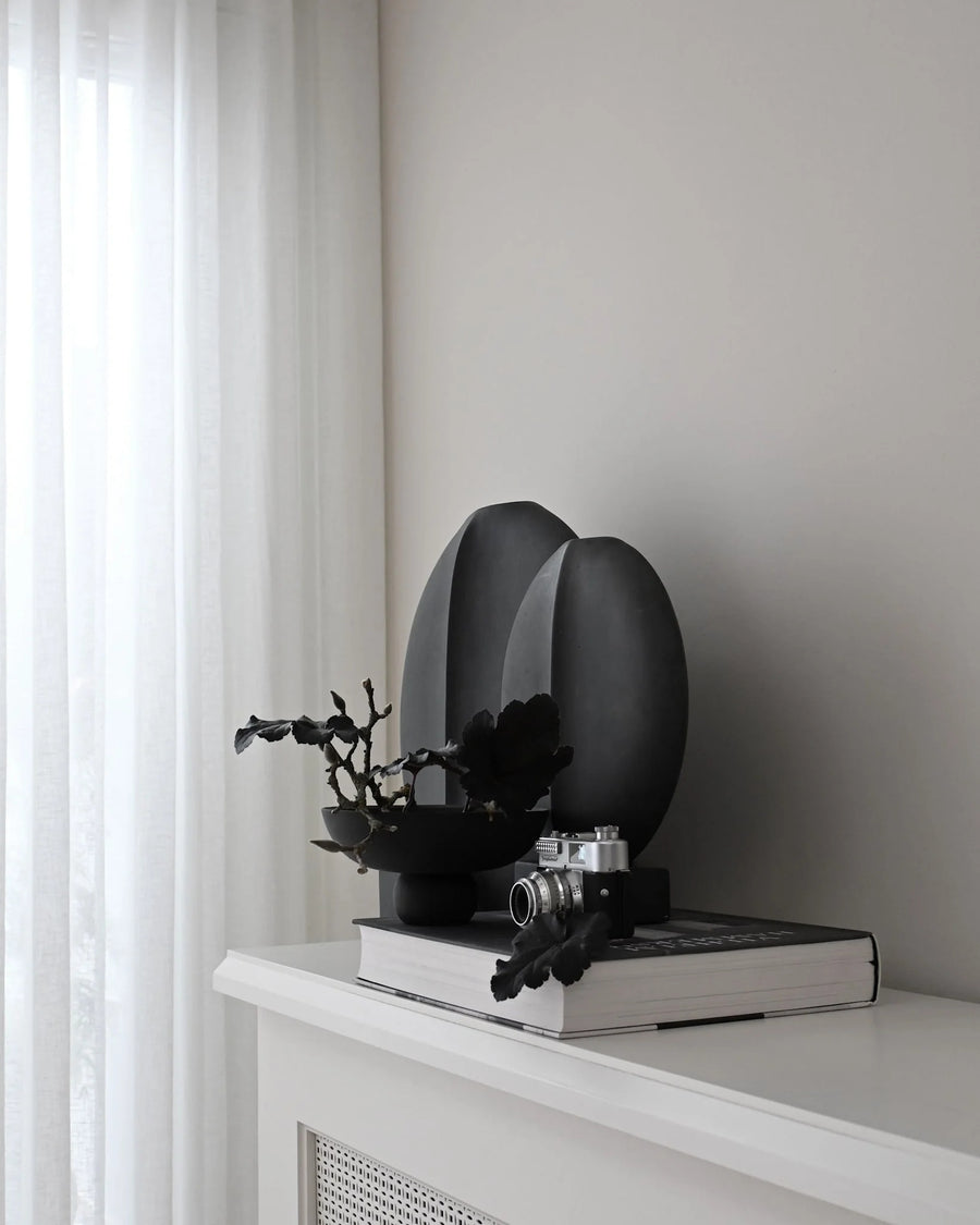 Black decorative object on a white surface with a neutral background from 101 Copenhagen at Spacio retail stores in Mumbai & Kolkata. 