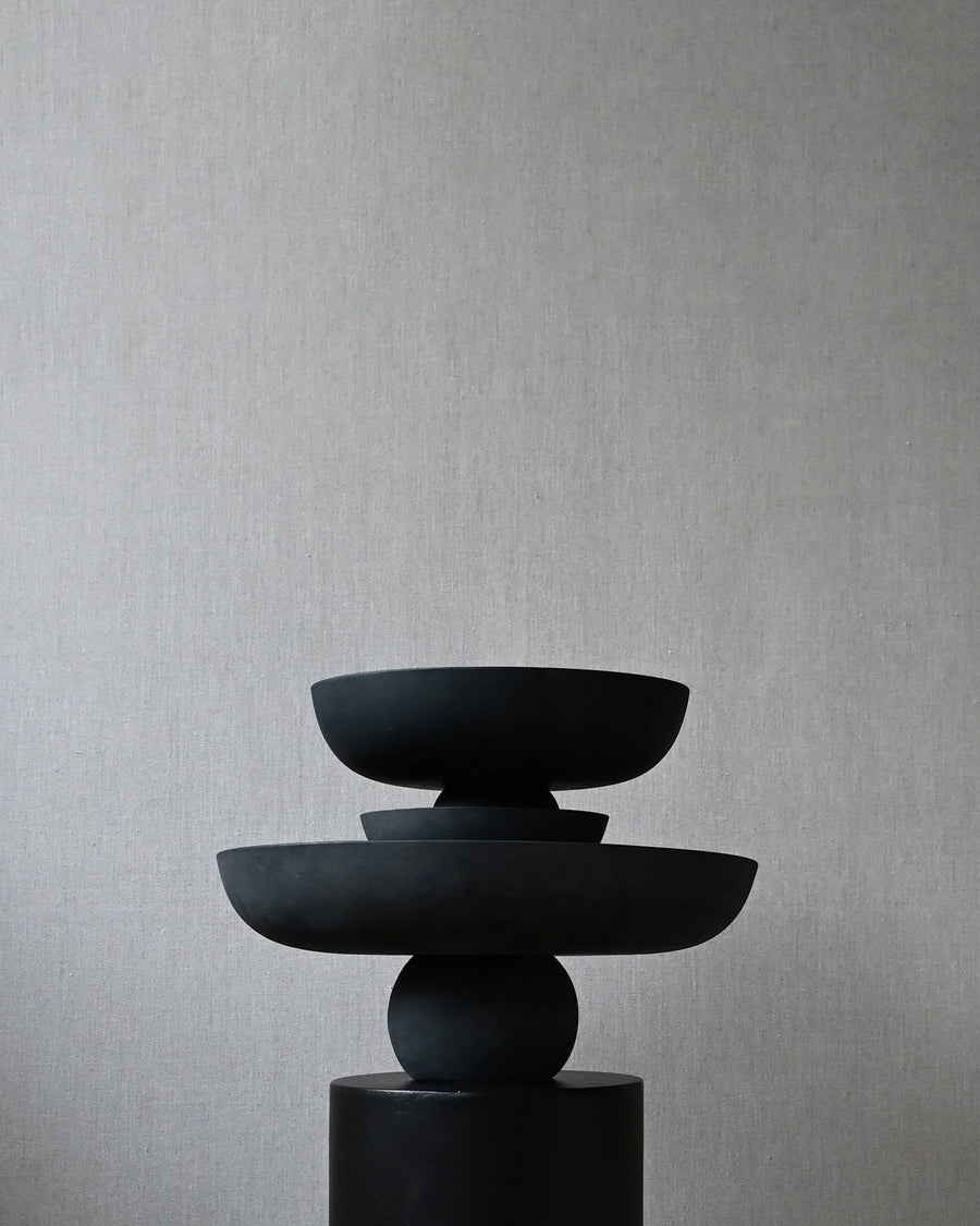 Stack of black ceramic bowls on a gray background from 101 Copenhagen at Spacio retail stores in Mumbai & Kolkata. 
