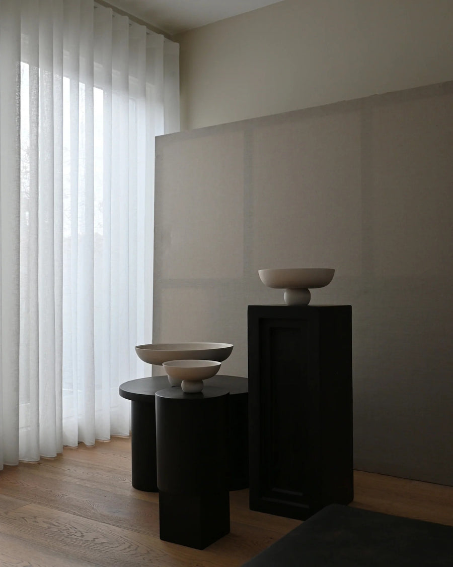 Three ceramic bowls on black pedestals against a neutral wall with white curtains from 101 Copenhagen at Spacio retail stores in Mumbai & Kolkata. 