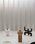 A group of 101Cph Cobra Candle Holder Black 223071 by 101 Copenhagen in front of a curtain, showcasing stylish interior silhouettes.