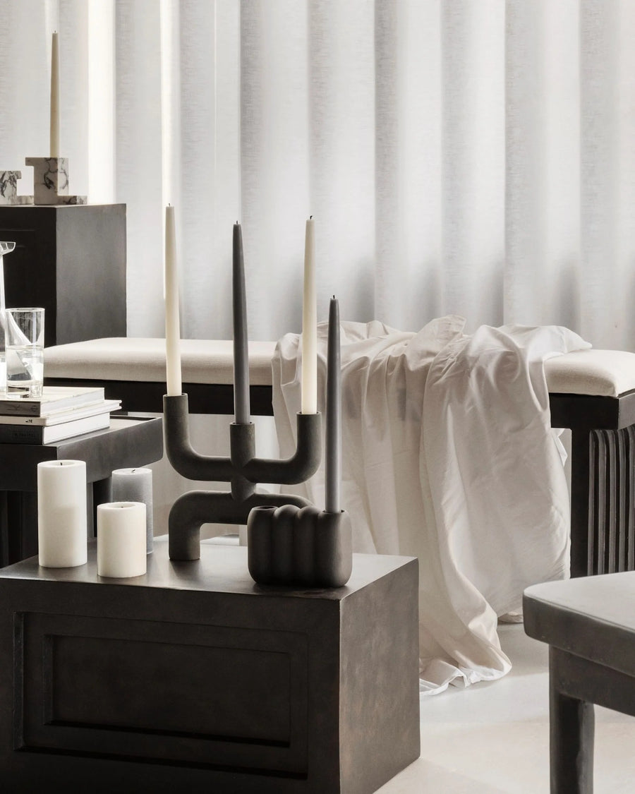 Modern interior with dark wooden furniture, white curtains, and candles.