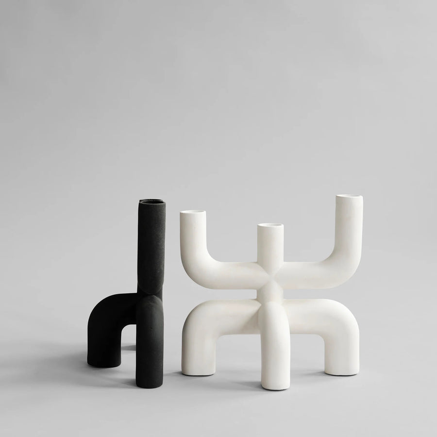 Two modern candle holders, one black and one white, on a light gray background from 101 Copenhagen at Spacio retail stores in Mumbai & Kolkata. 