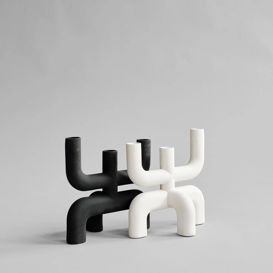 Two modern candle holders, one black and one white, on a light gray background from 101 Copenhagen at Spacio retail stores in Mumbai & Kolkata. 