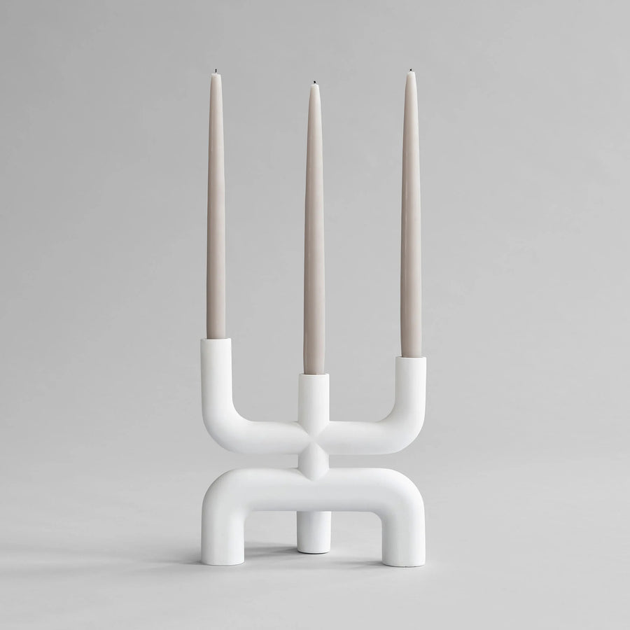 White candle holder with three candles on a gray background from 101 Copenhagen at Spacio retail stores in Mumbai & Kolkata. 