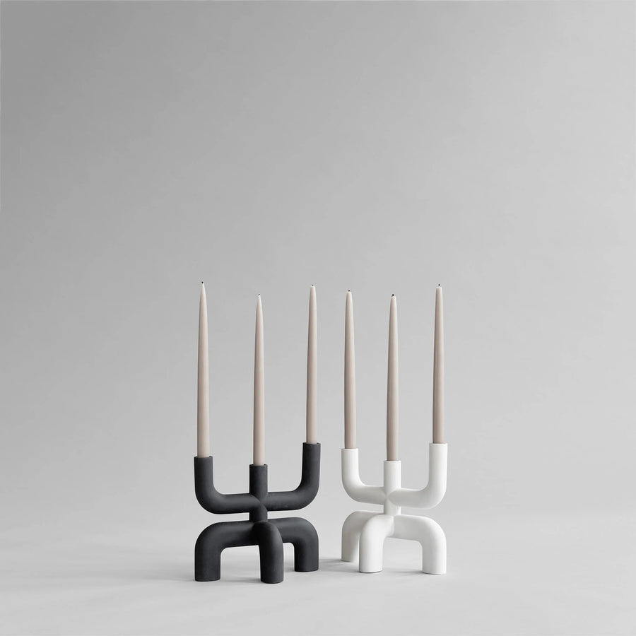 Two modern candle holders with candles on a gray background from 101 Copenhagen at Spacio retail stores in Mumbai & Kolkata. 