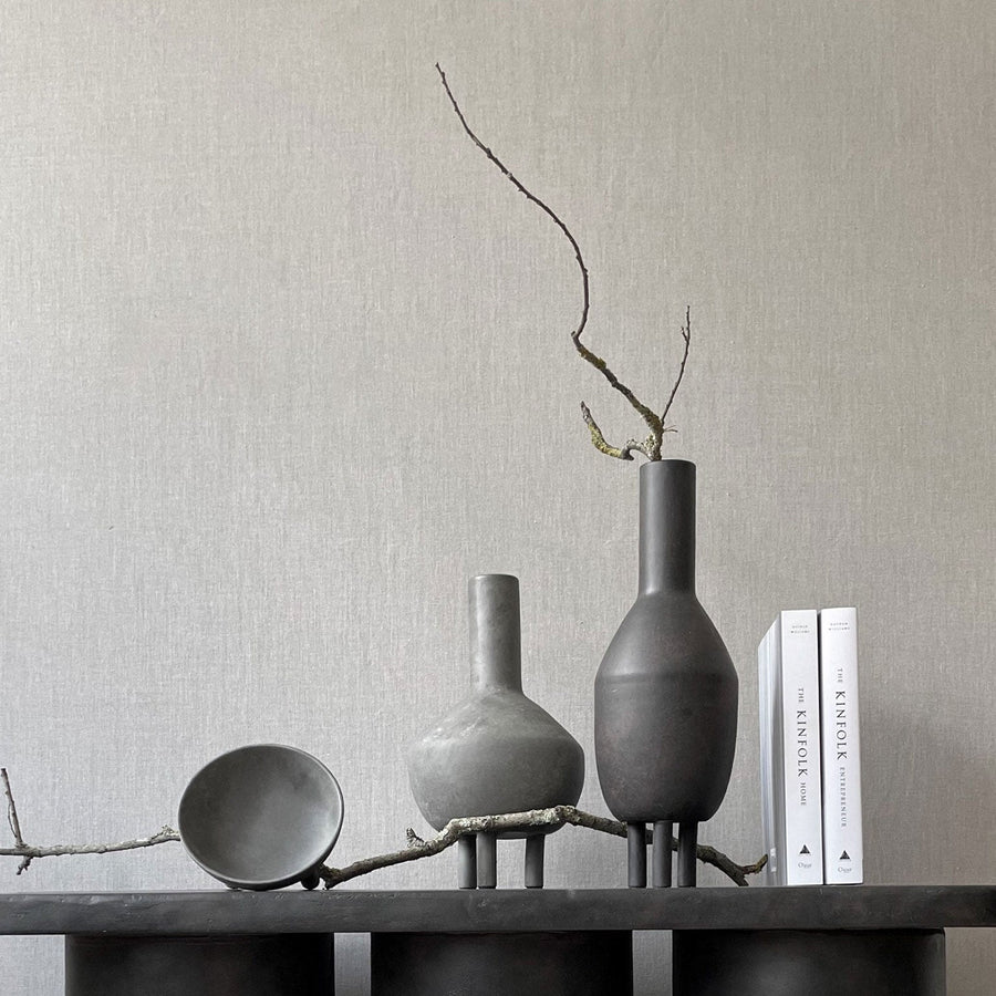 A 101Cph Duck Fat Dark Grey 111281 table adorned with vases and books, embracing the Cobra Arts Movement aesthetic. (Brand Name: 101 Copenhagen)