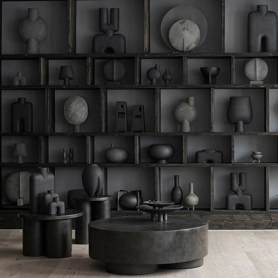 A room with many 101Cph Duck Fat Dark Grey 111281 vases and a coffee table in a dark grey color.