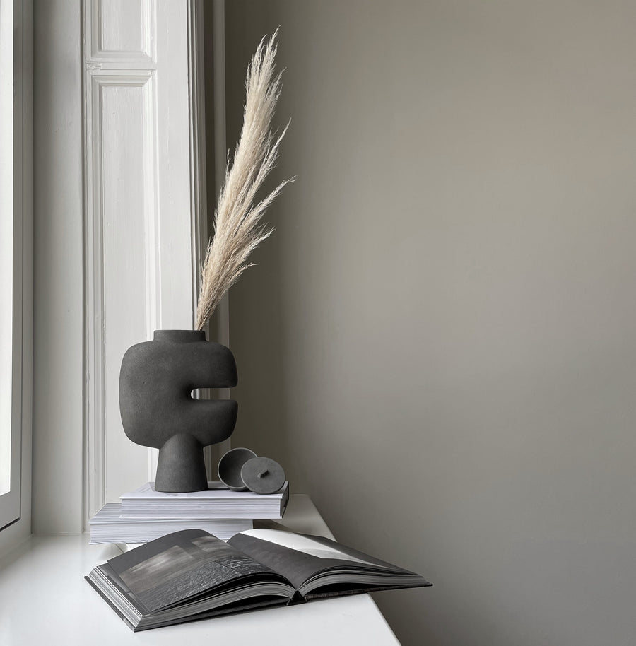 Decorative vase with dried plant on a book against a neutral wall from 101 Copenhagen at Spacio retail stores in Mumbai & Kolkata. 