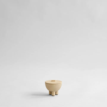 Small beige ceramic bowl with a lid on a light gray background from 101 Copenhagen at Spacio retail stores in Mumbai & Kolkata. 