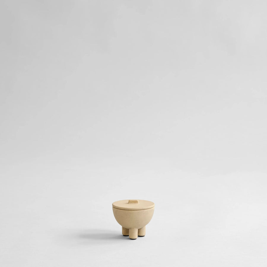 Small beige ceramic bowl with a lid on a light gray background from 101 Copenhagen at Spacio retail stores in Mumbai & Kolkata. 
