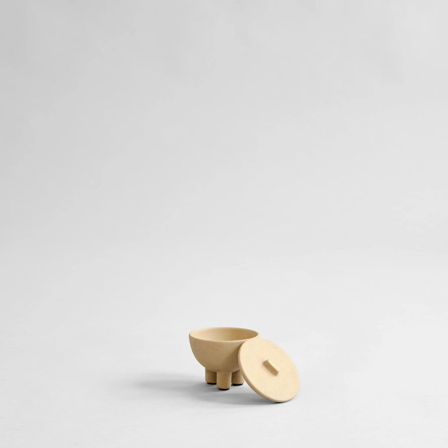Small beige ceramic bowl with a lid on a light gray background from 101 Copenhagen at Spacio retail stores in Mumbai & Kolkata. 