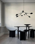 A black 101Cph Duck Plate Big Coffee 214049 table and chairs in a room with white walls, creating a Scandinavian home aesthetic.