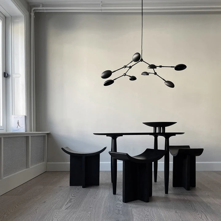 A black 101Cph Duck Plate Big Coffee 214049 table and chairs in a room with white walls, creating a Scandinavian home aesthetic.