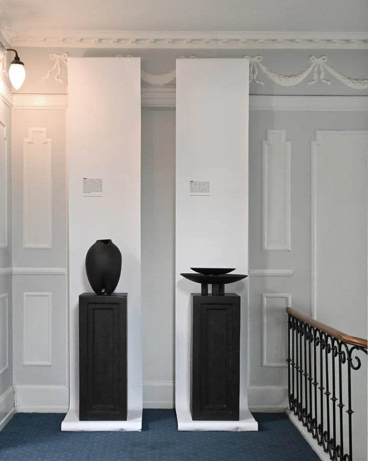 Two black vases, one resembling the 101Cph Duck Plate Mini Coffee 214048 design, are elegantly showcased in a Scandinavian home.