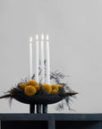 A black 101Cph Duck Plate Mini Coffee 214048 candle holder with yellow pom poms and candles, perfect for creating a cozy Scandinavian home atmosphere.