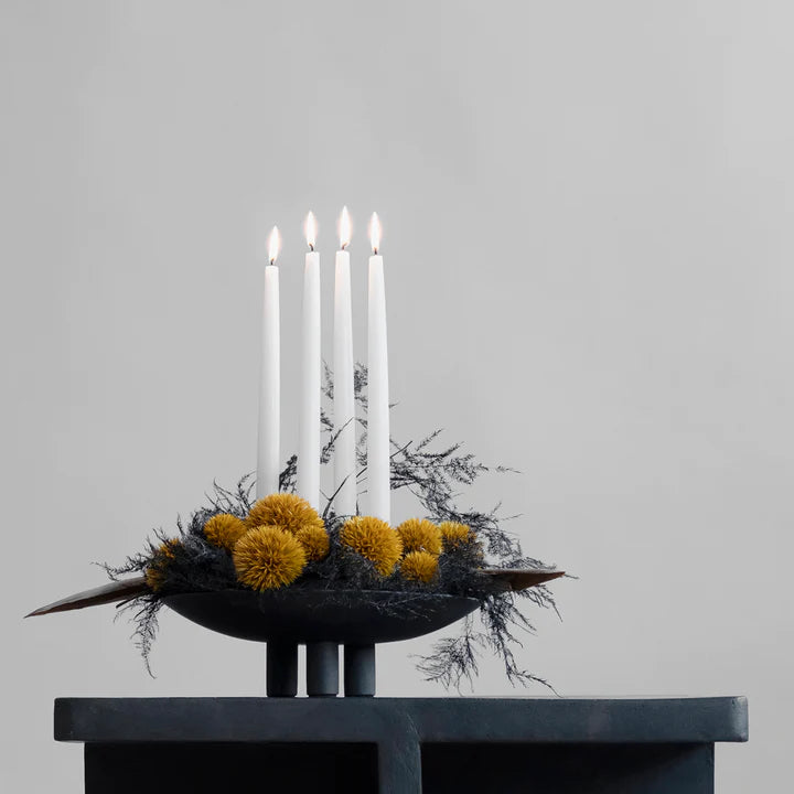 A black 101Cph Duck Plate Mini Coffee 214048 candle holder with yellow pom poms and candles, perfect for creating a cozy Scandinavian home atmosphere.