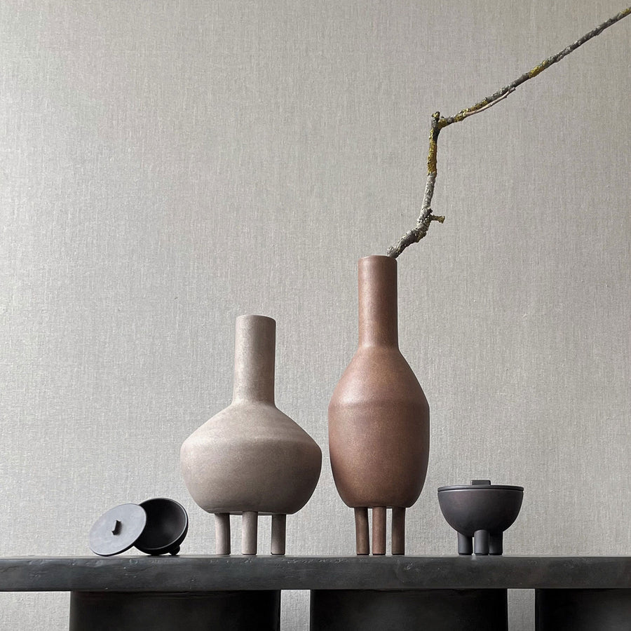 Quirky vases, including the 101Cph Duck Vase Fat Taupe 213045 by 101 Copenhagen, displayed on a table next to a wall.