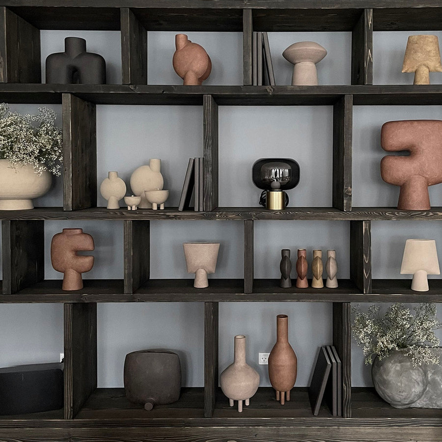 A shelf filled with a wide variety of quirky vases, including the 101Cph Duck Vase Fat Taupe 213045 by 101 Copenhagen, showcasing the unique and creative pieces inspired by the Cobra Arts Movement.