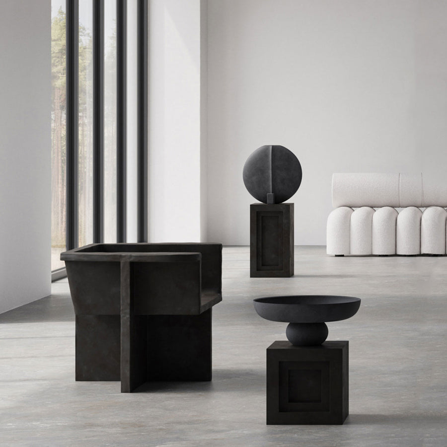 A modern living room with a 101Cph Guggenheim Big Black 203004 table from the brand 101 Copenhagen and quirky vases.
