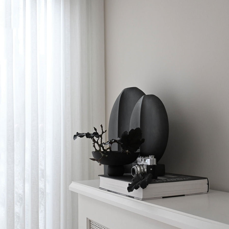 A quirky 101Cph Guggenheim Big Black 203004 vase by 101 Copenhagen sits on a mantle in an interior setting.