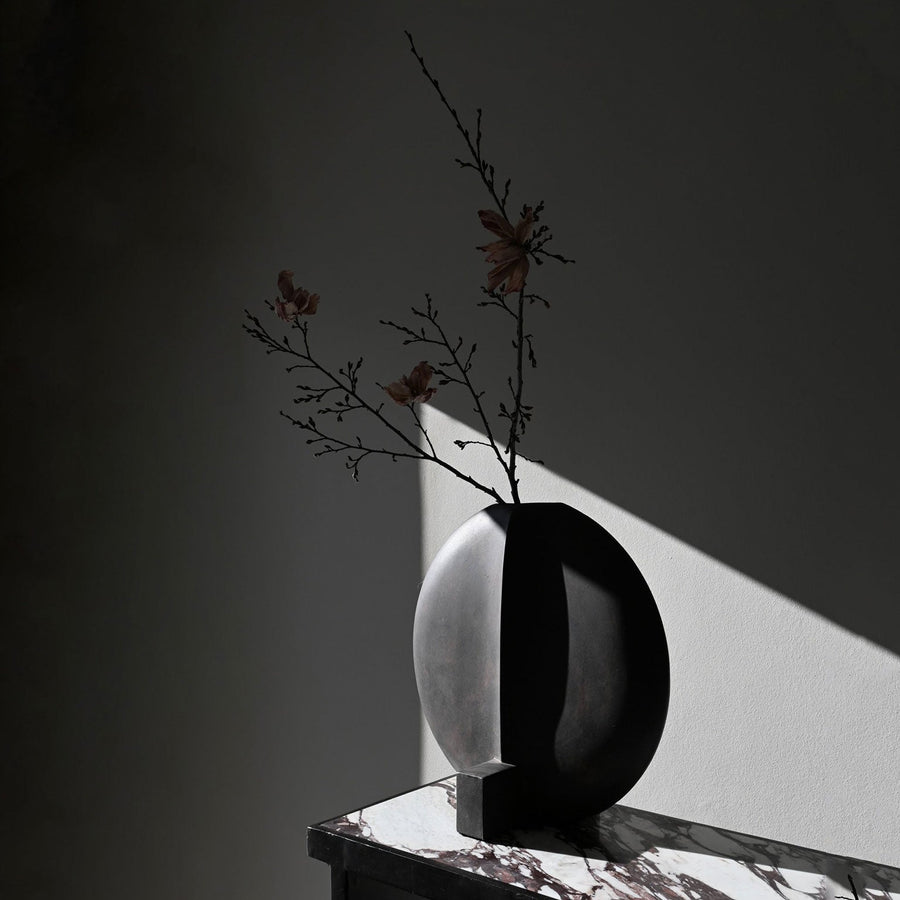 A 101Cph Guggenheim Big Coffee 111219 vase sits on top of a marble table, adding a touch of elegance to the coffee-coloured room. (Brand Name: 101 Copenhagen)