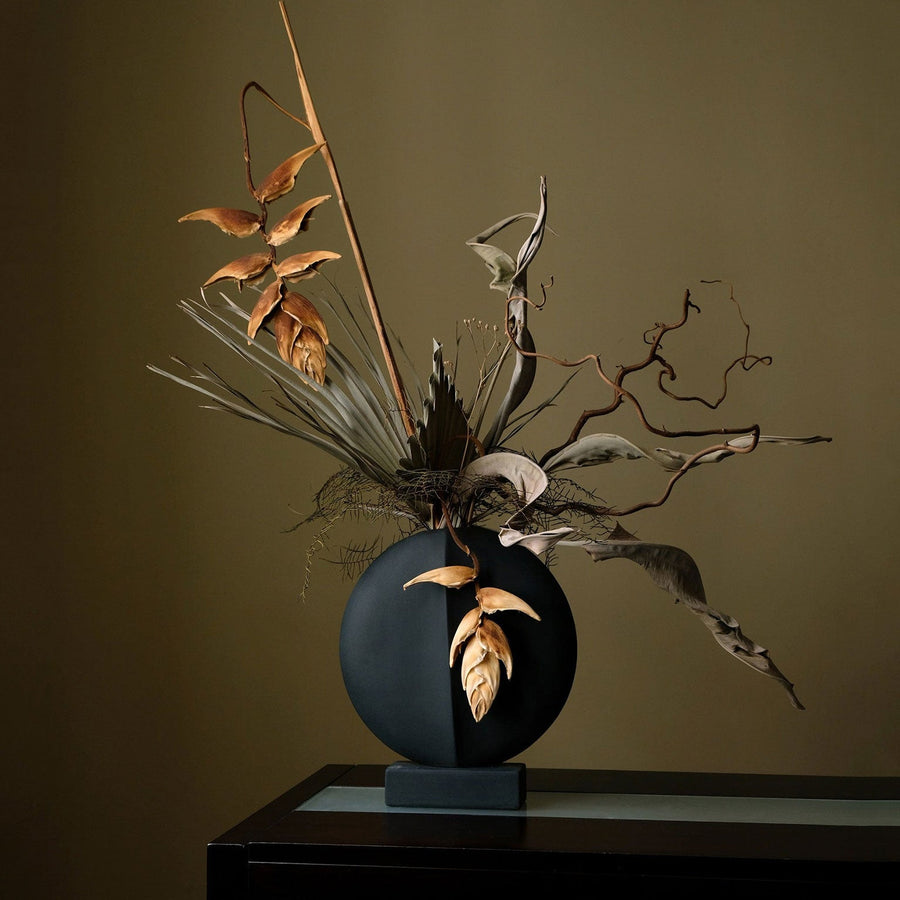 A whimsical 101Cph Guggenheim Mini Black 111126 vase with a bunch of leaves in it, perfect for adding a quirky touch to any interior setting. (brand: 101 Copenhagen)