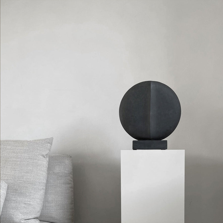 In an interior setting, a whimsical 101Cph Guggenheim Mini Black 111126 from 101 Copenhagen sits atop a white pedestal, resembling quirky vases.