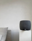 A handcrafted 101Cph Guggenheim Square Coffee 111124 vase sits on top of a pedestal in a room.