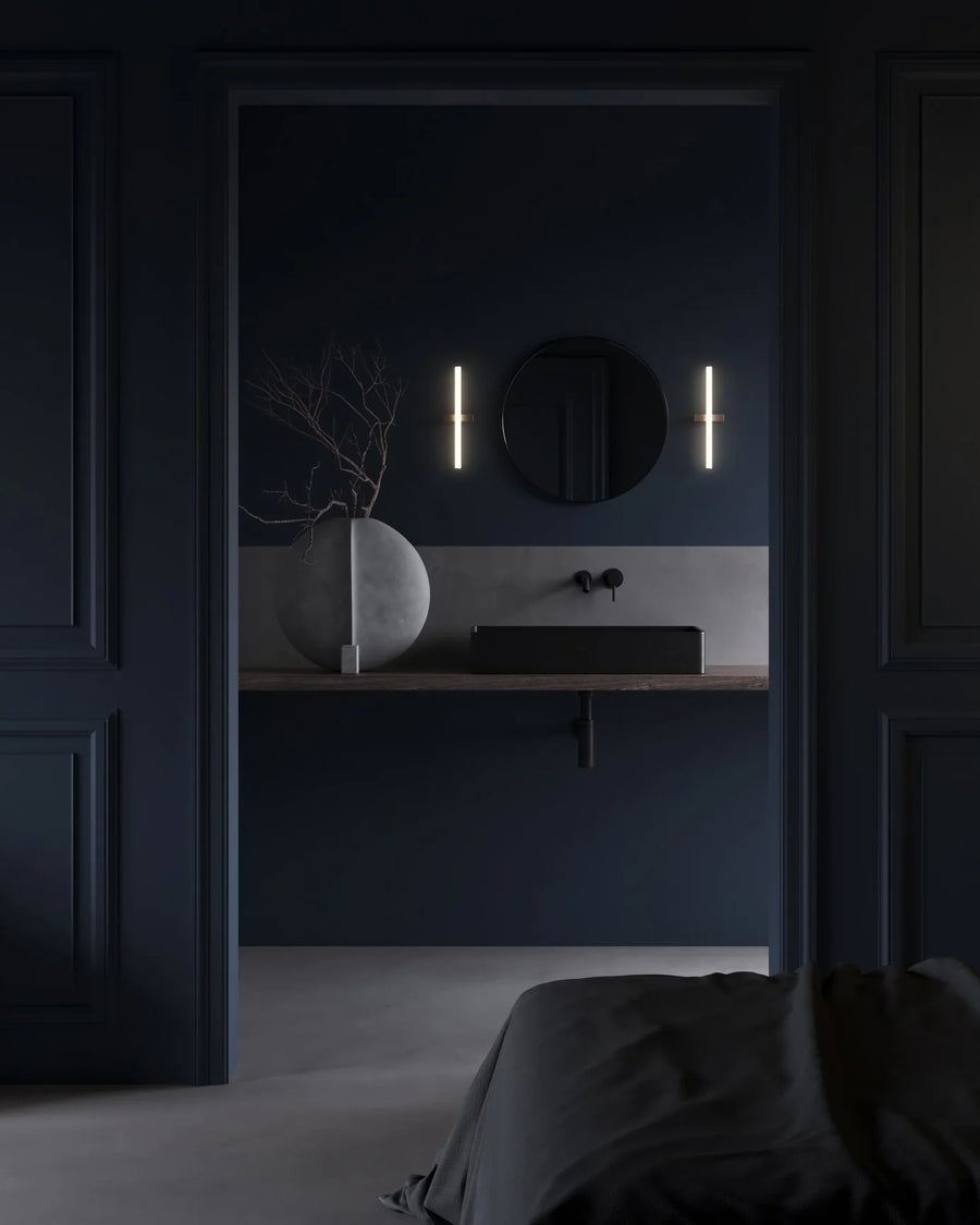 Modern bathroom with dark blue walls, round mirror, and sculptural vase from 101 Copenhagen