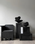 A black chair sits on a wooden floor, accompanied by a 101Cph Medusa Tray Mini Coffee 221064 from the brand 101 Copenhagen.