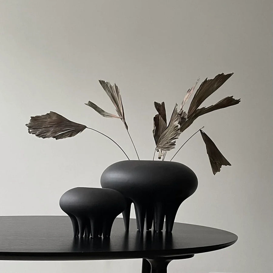 A 101 Copenhagen Medusa Vase Big Coffee 221061 sits on a table in front of a white wall.
