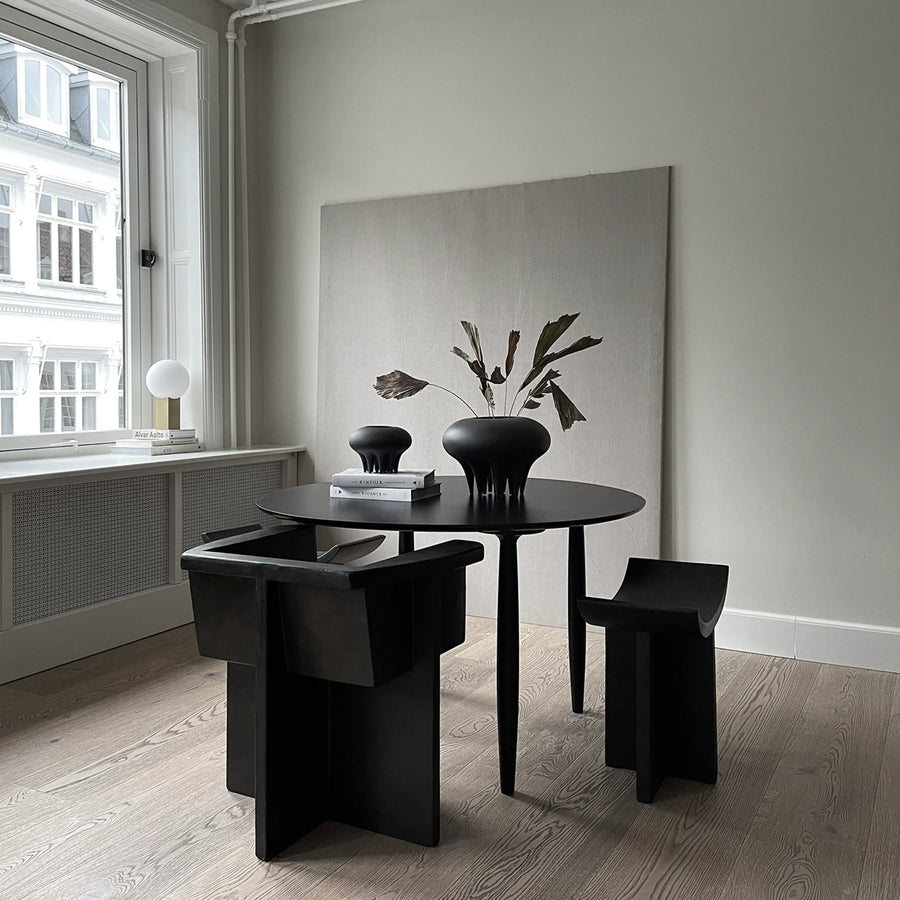 A dining room with a black table and chairs featuring a 101Cph Medusa Vase Mini Coffee 221062 by 101 Copenhagen as the centerpiece.