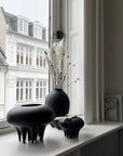 A 101Cph Medusa Vase Mini Coffee 221062 by 101 Copenhagen sits on a window sill in front of a window.