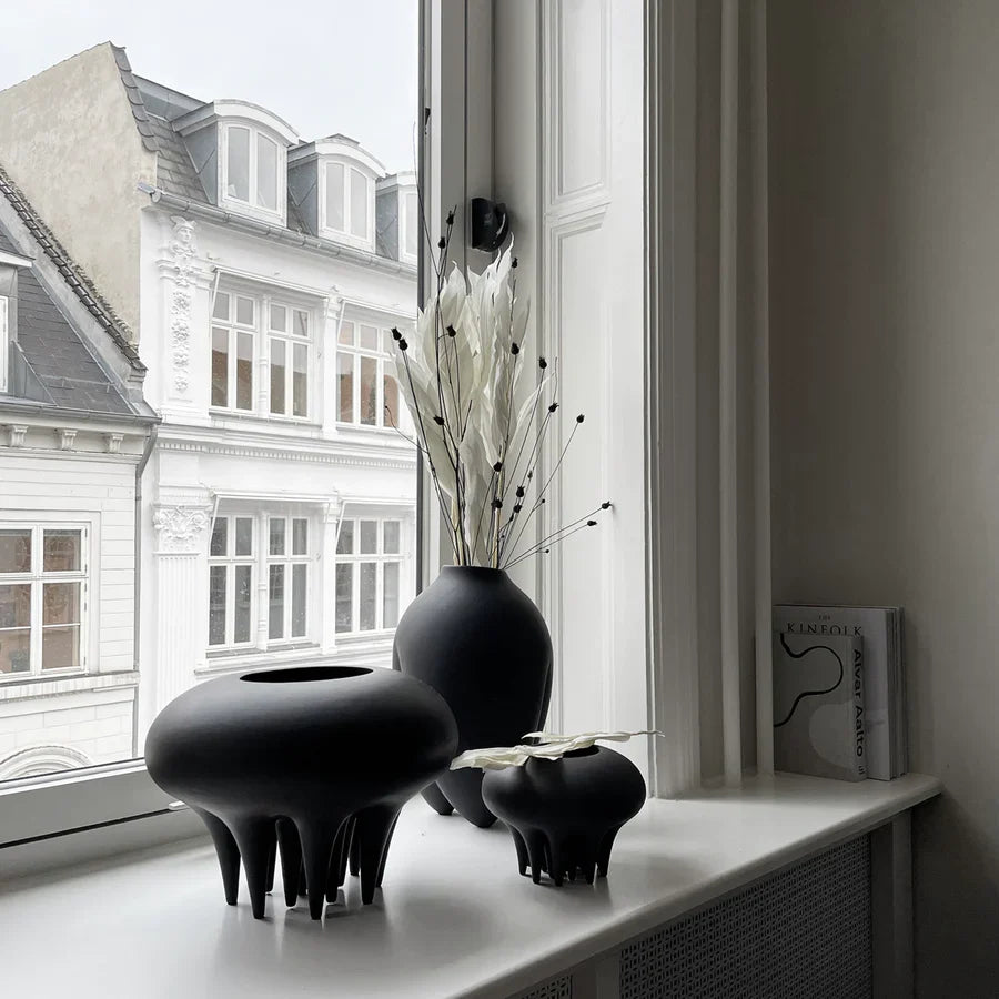 A 101Cph Medusa Vase Mini Coffee 221062 by 101 Copenhagen sits on a window sill in front of a window.