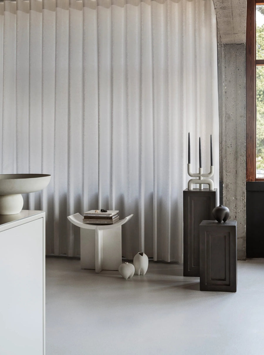 Modern interior with a curtain, table and decor accessories on coffee colour pedestals from 101 Copenhagen