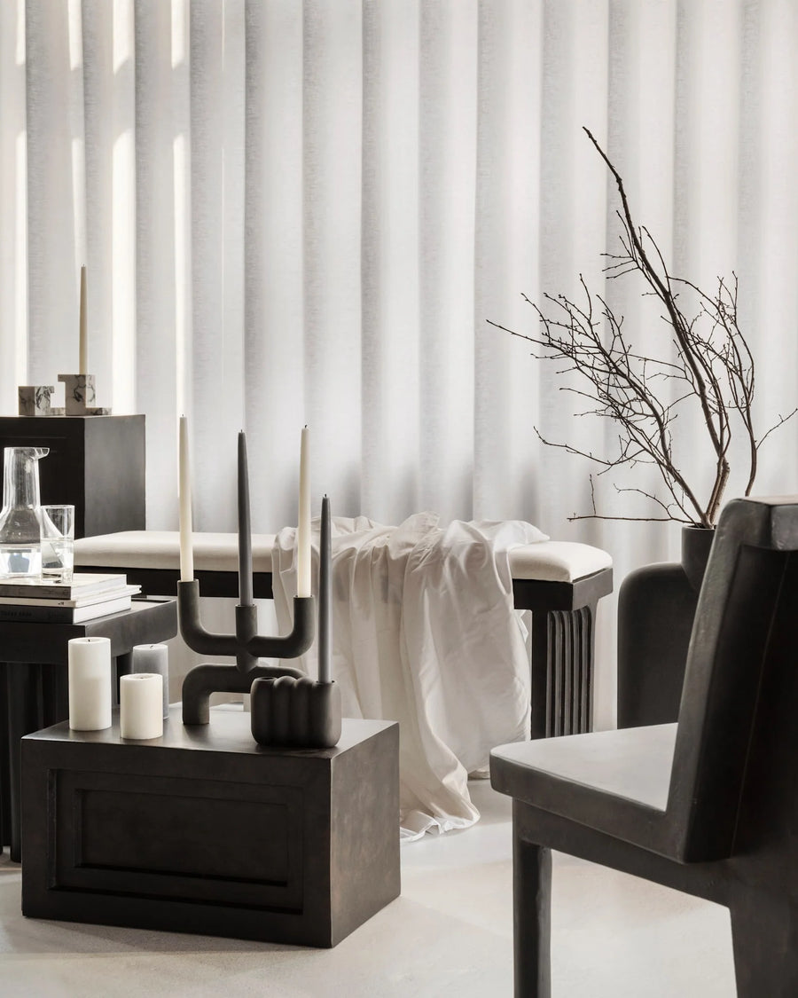 Modern interior with black furniture, a plant against a white curtain and stands on a pedestal (plinth) from 101 Copenhagen