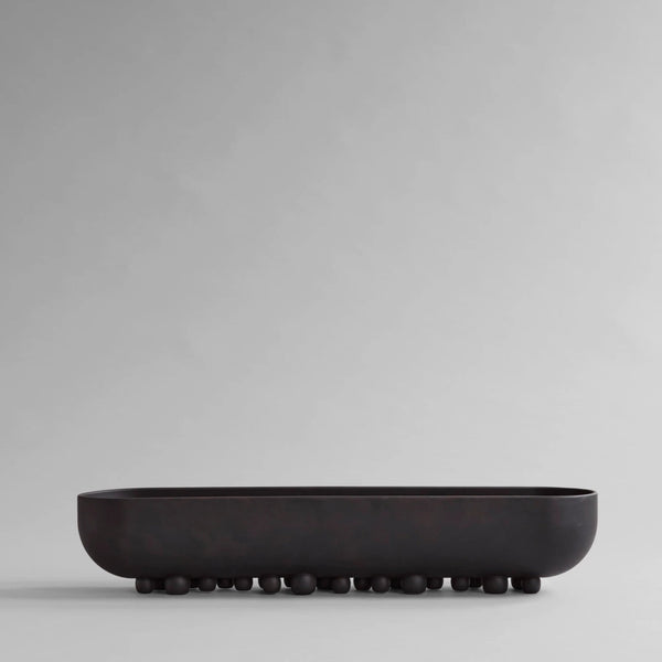 Black ceramic bowl on a light gray background from 101 Copenhagen at Spacio retail stores in Mumbai & Kolkata. 