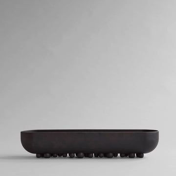 Black ceramic bowl on a light gray background from 101 Copenhagen at Spacio retail stores in Mumbai & Kolkata. 