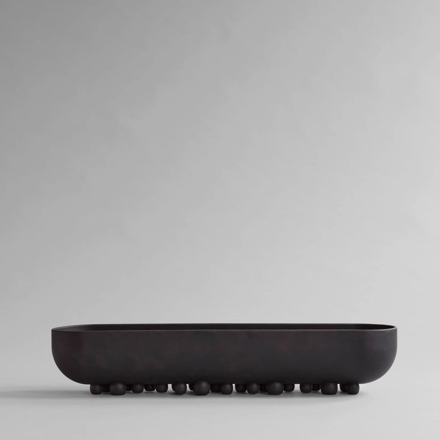 Black ceramic bowl on a light gray background from 101 Copenhagen at Spacio retail stores in Mumbai & Kolkata. 