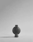 A 101Cph Sphere Bubl Mini Dark Grey 111029 finished vase, part of the Scandinavian brand 101 Copenhagen, sitting on a grey background.