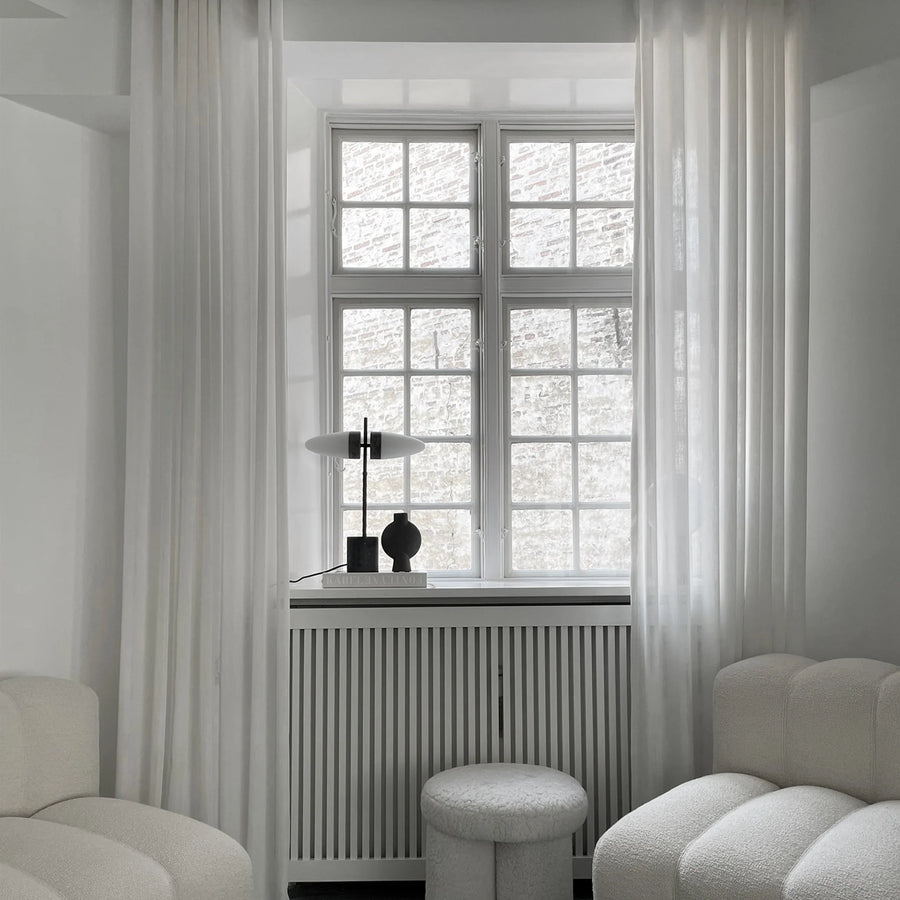 A room with white furniture and a window featuring a dark grey finish on the 101 Copenhagen brand 101Cph Sphere Bubl Mini Dark Grey 111029 Vase.