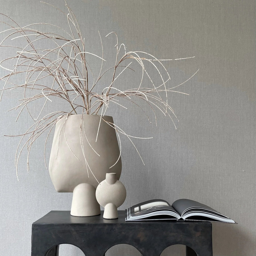 A 101 Copenhagen Sphere Bubl Mini Sand 203008 vase, placed on a table next to a book.