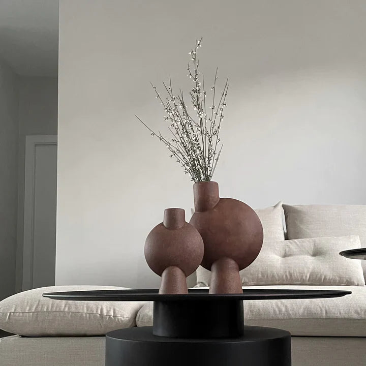 A living room with two 101Cph Sphere Bubl Mini Terracotta 203010 vases by 101 Copenhagen on a table.