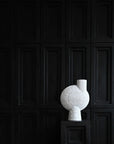 A decorative 101Cph Sphere Bubl Shisen Big B White 231013 sculpture, by 101 Copenhagen, sits on top of a black pedestal in a sculptural manner.