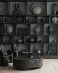 Dark gray abstract sculptures on shelves in a minimalistic room.