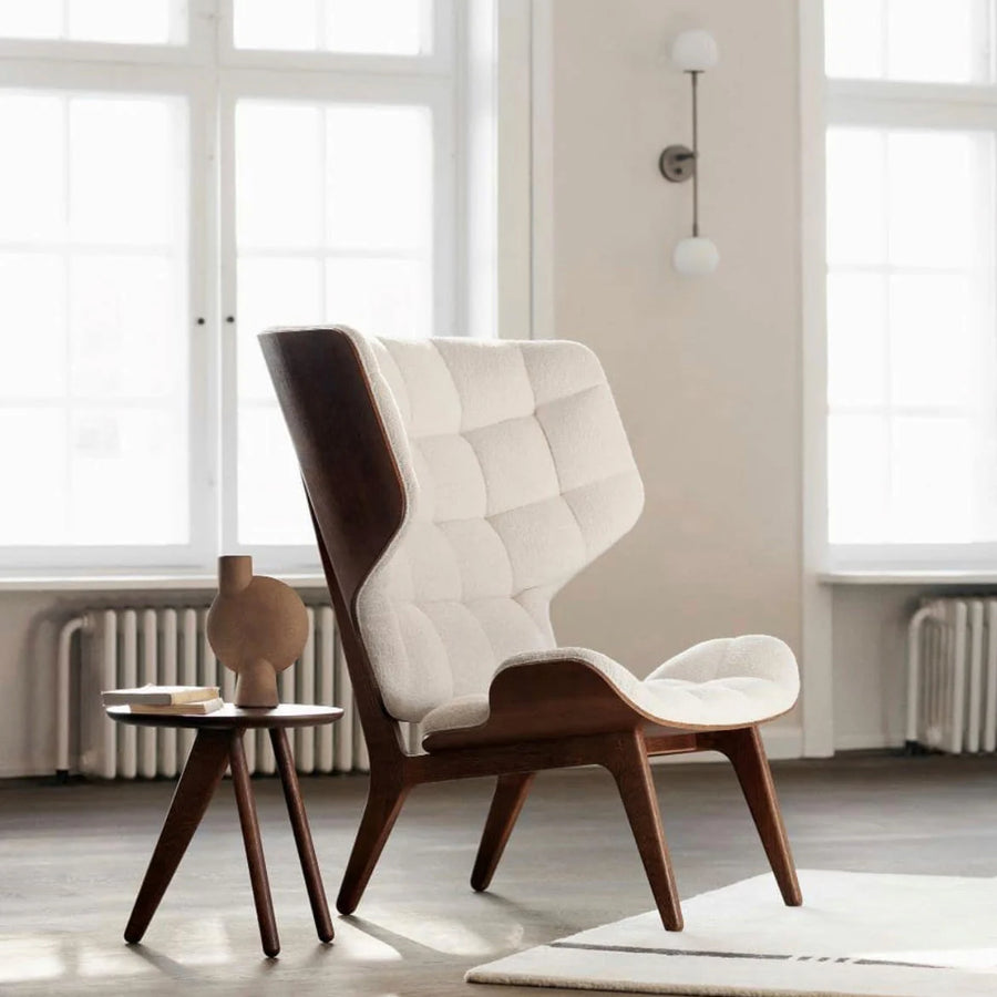 Modern chair with white cushion in a bright room with large windows and a 101 Copenhagen sculptural vase. 