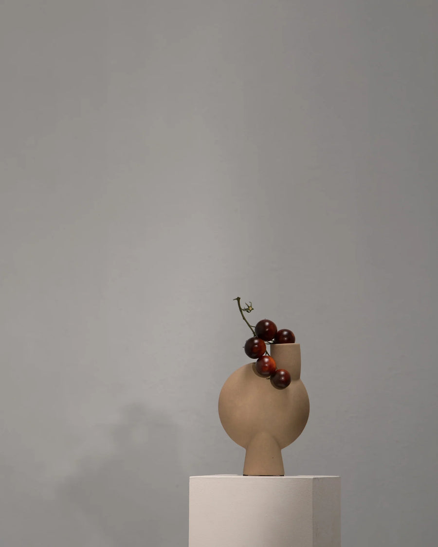 Vase with grapes on a sculptural vase against a gray background from 101 Copenhagen at Spacio retail stores in Mumbai & Kolkata. 
