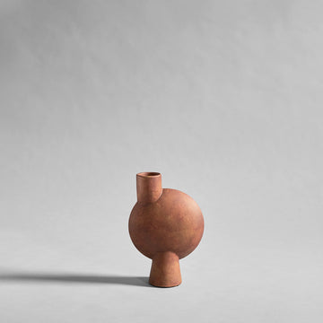 Terracotta colour sculptural vase vase on a light gray background from 101 Copenhagen at Spacio retail stores in Mumbai & Kolkata. 